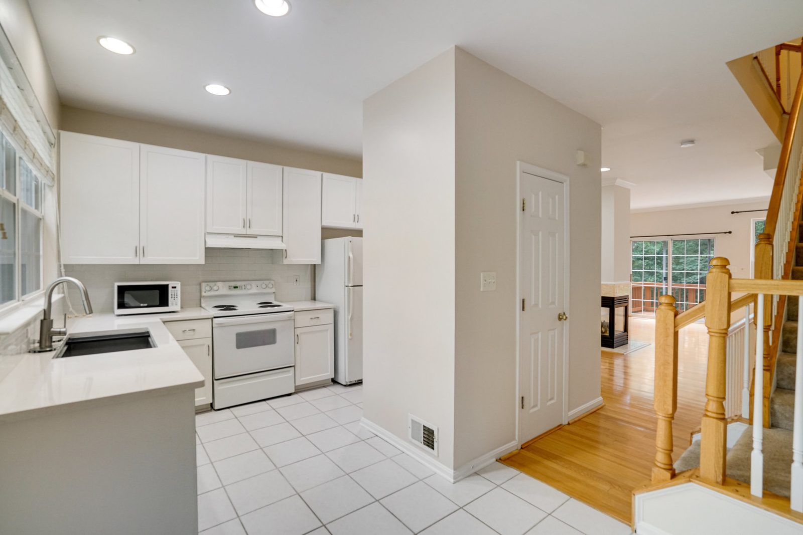 White kitchen with tile floor opening to hardwood living area