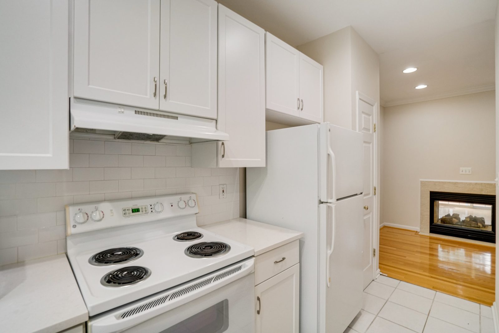 Kitchen with range hood, white appliances and tile flooring