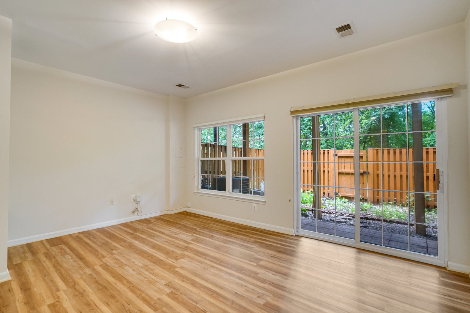 Room with wood-look plank floor and sliding door to fenced patio