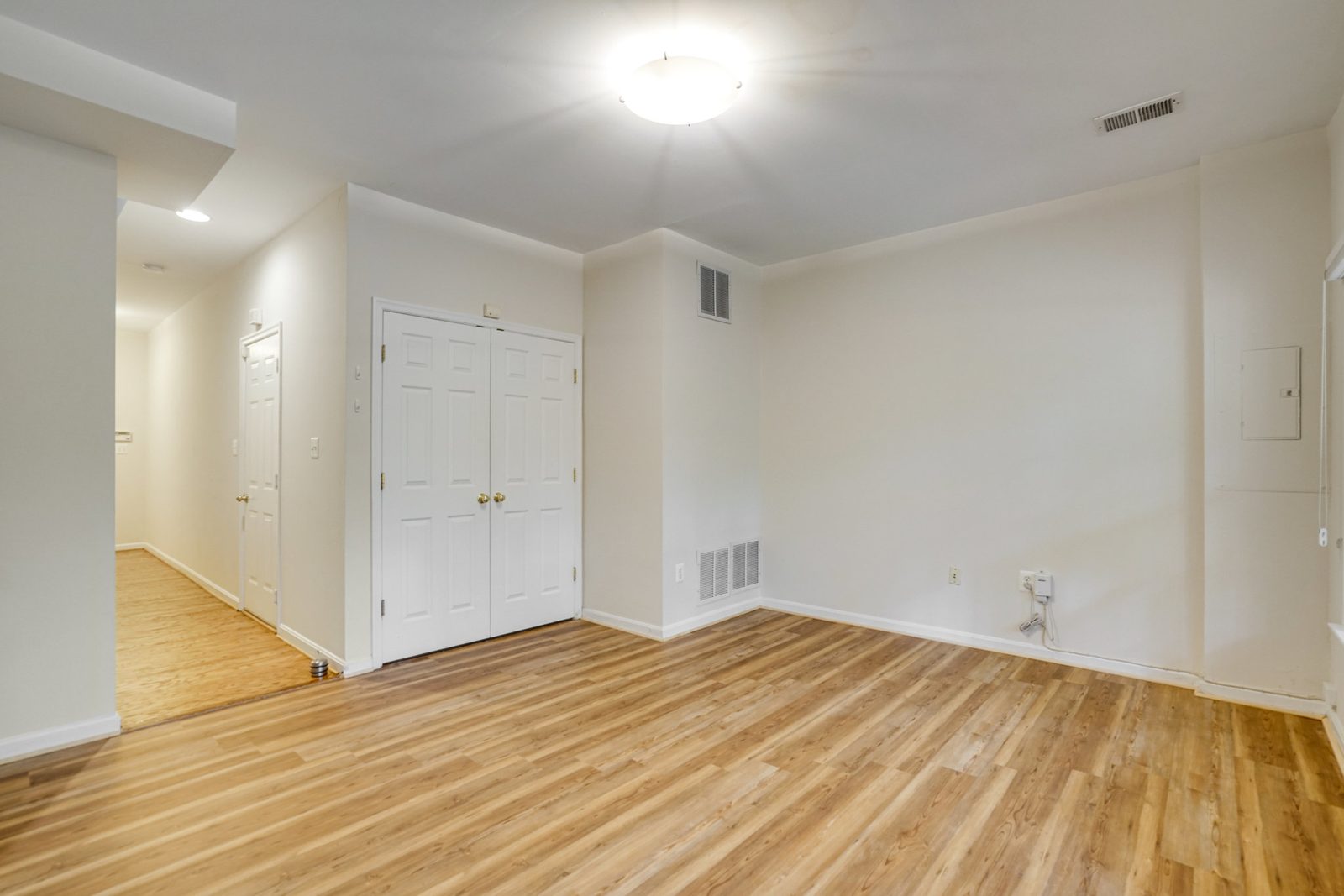 Empty room with wood-look plank floor and double closet doors
