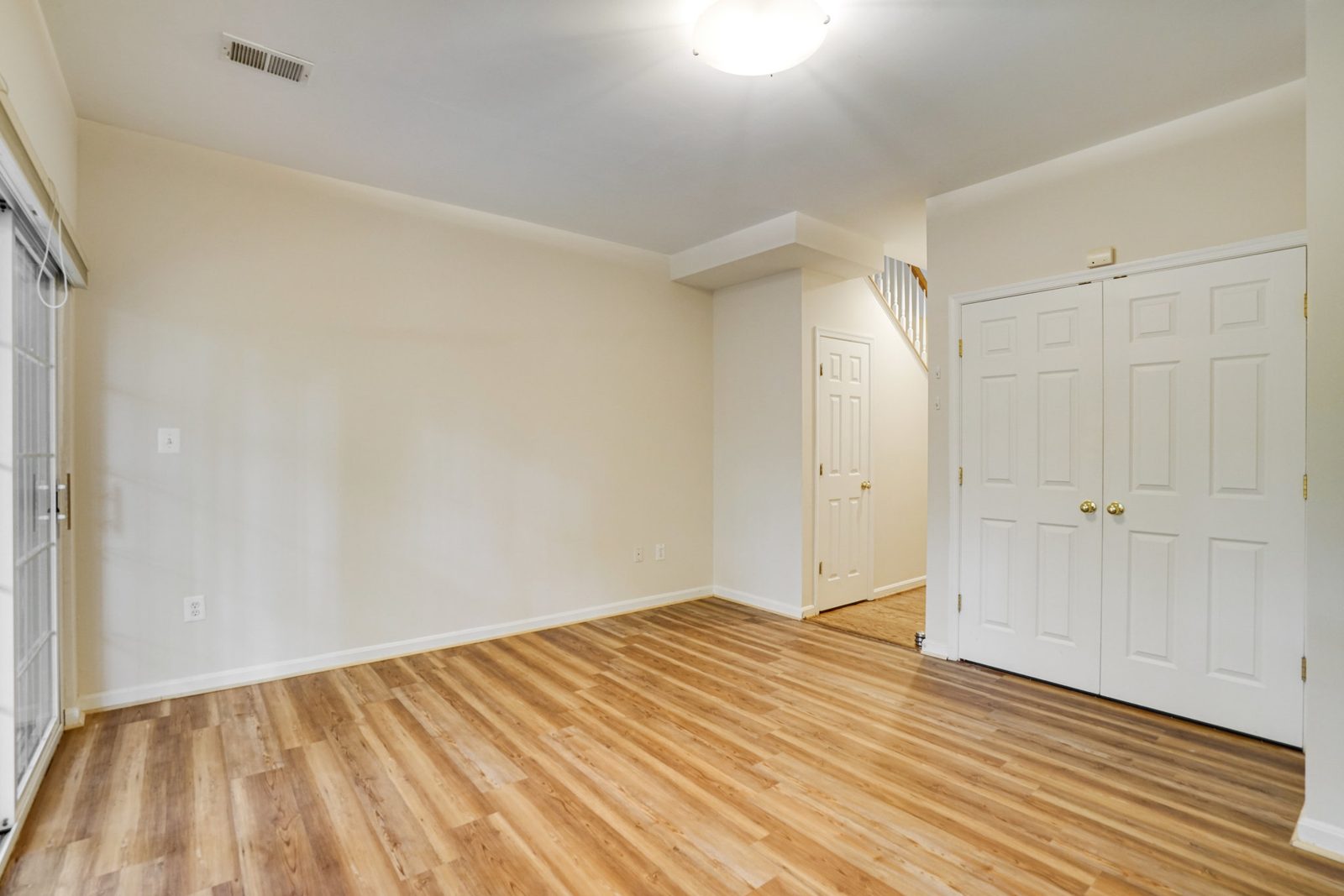 Room with plank flooring, closet doors and staircase beyond