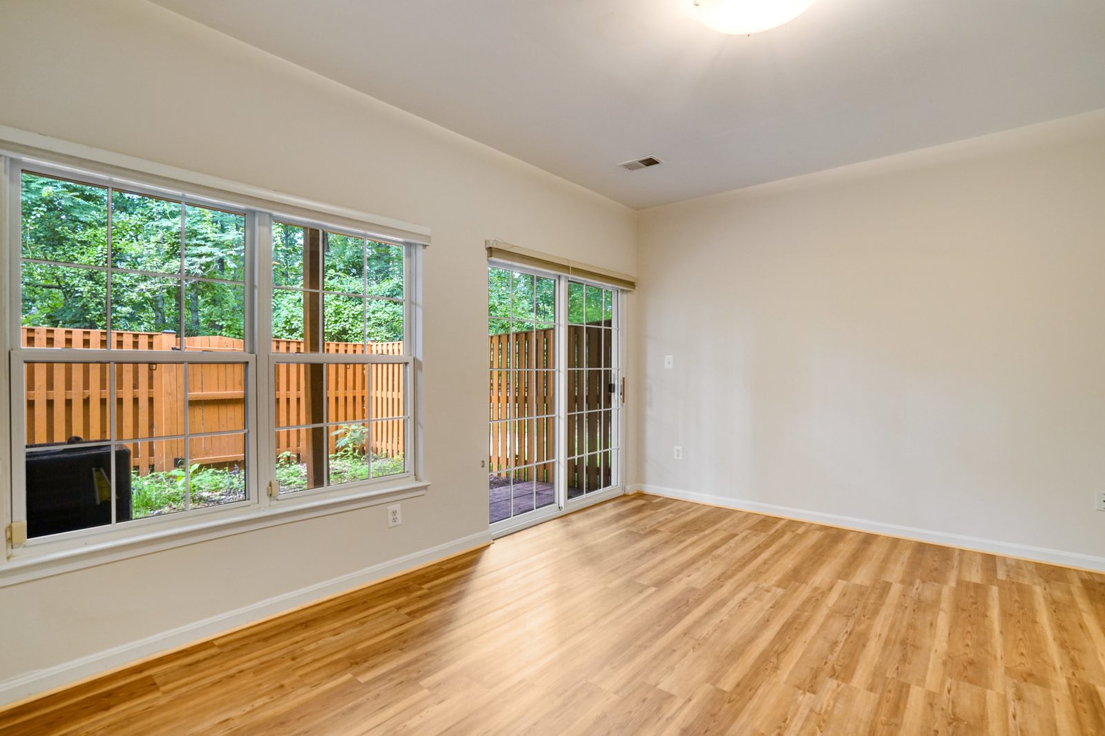 Empty room with wood-look floors and sliding door to fenced patio