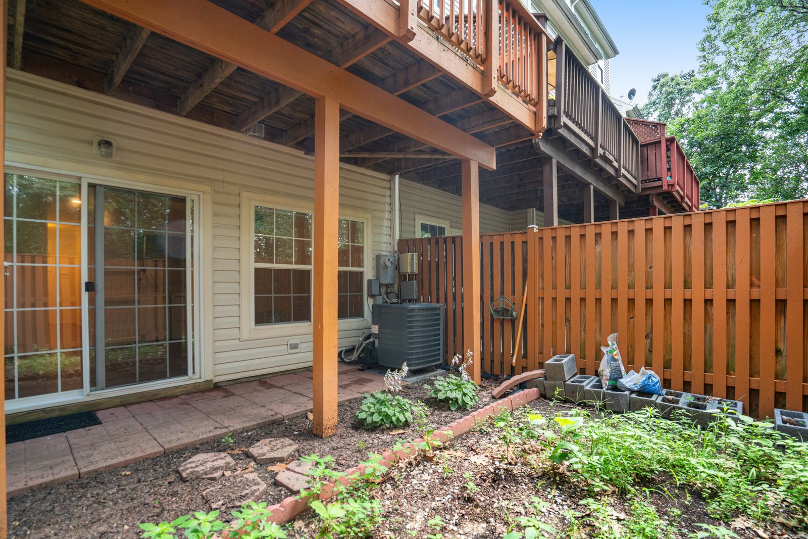 Rear patio under deck with sliding glass door and AC unit