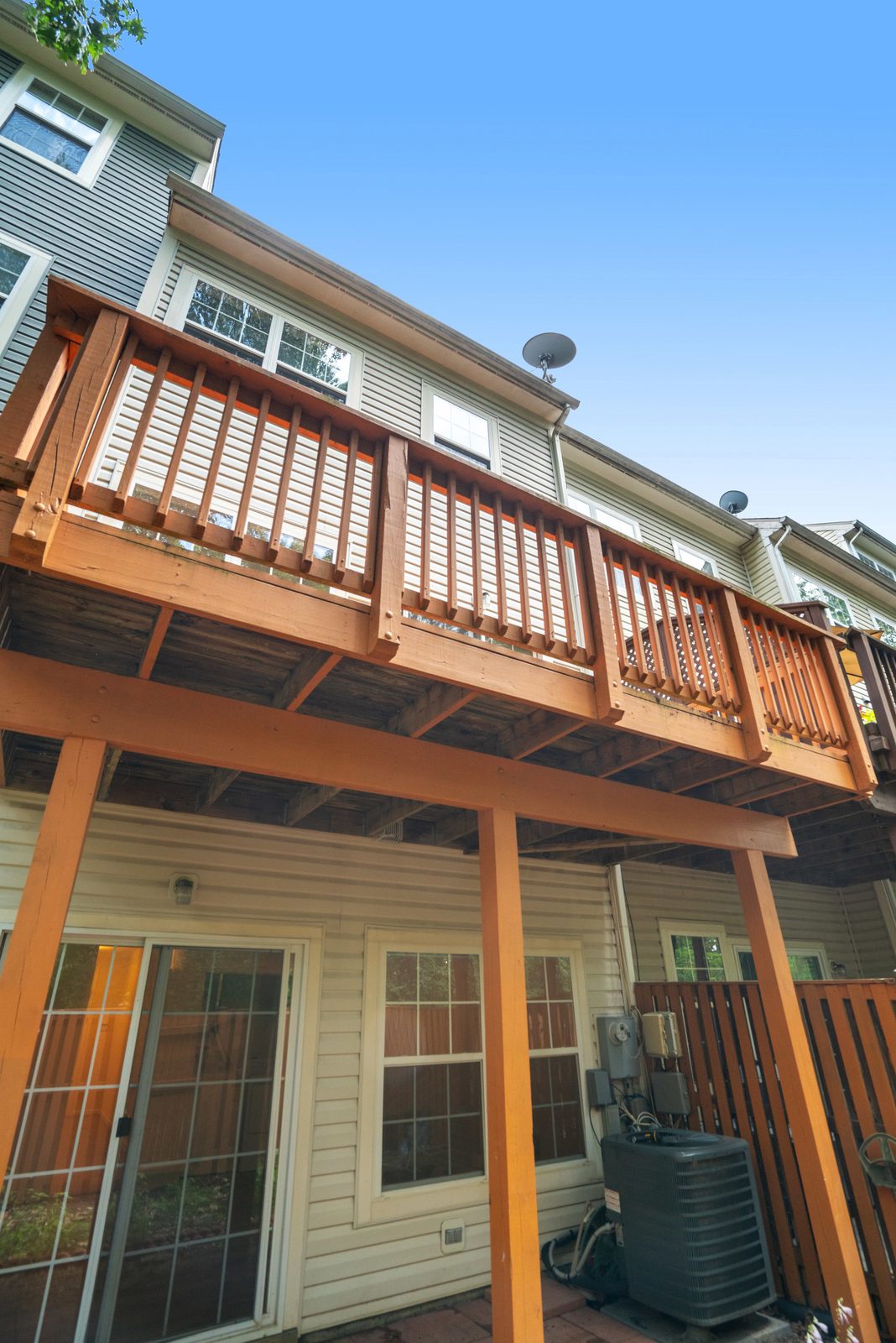 Rear exterior with elevated wood deck above covered patio