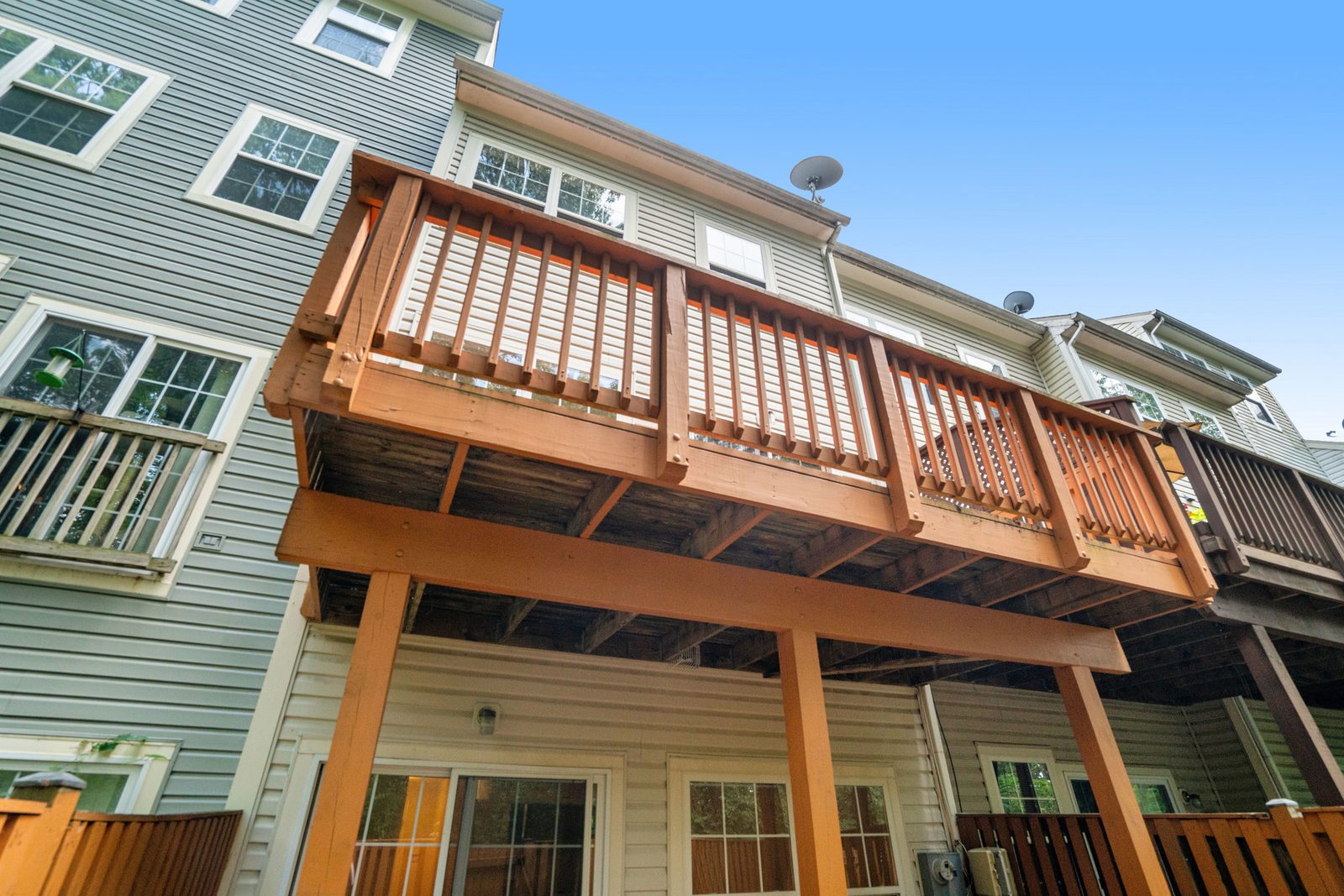 Elevated wood deck spanning rear elevation above covered patio
