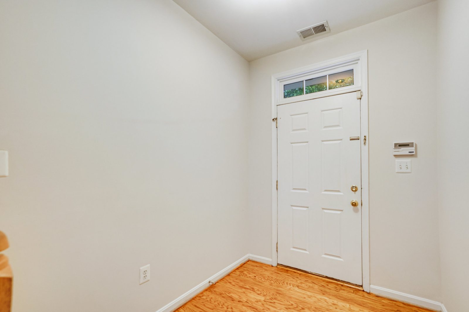 Entry foyer with white front door, transom window and hardwood floor