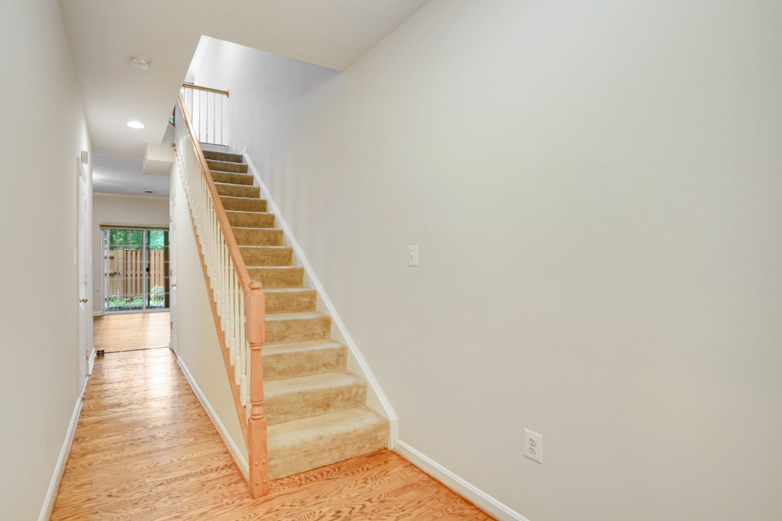 Hallway with carpeted staircase, white balusters and oak handrail