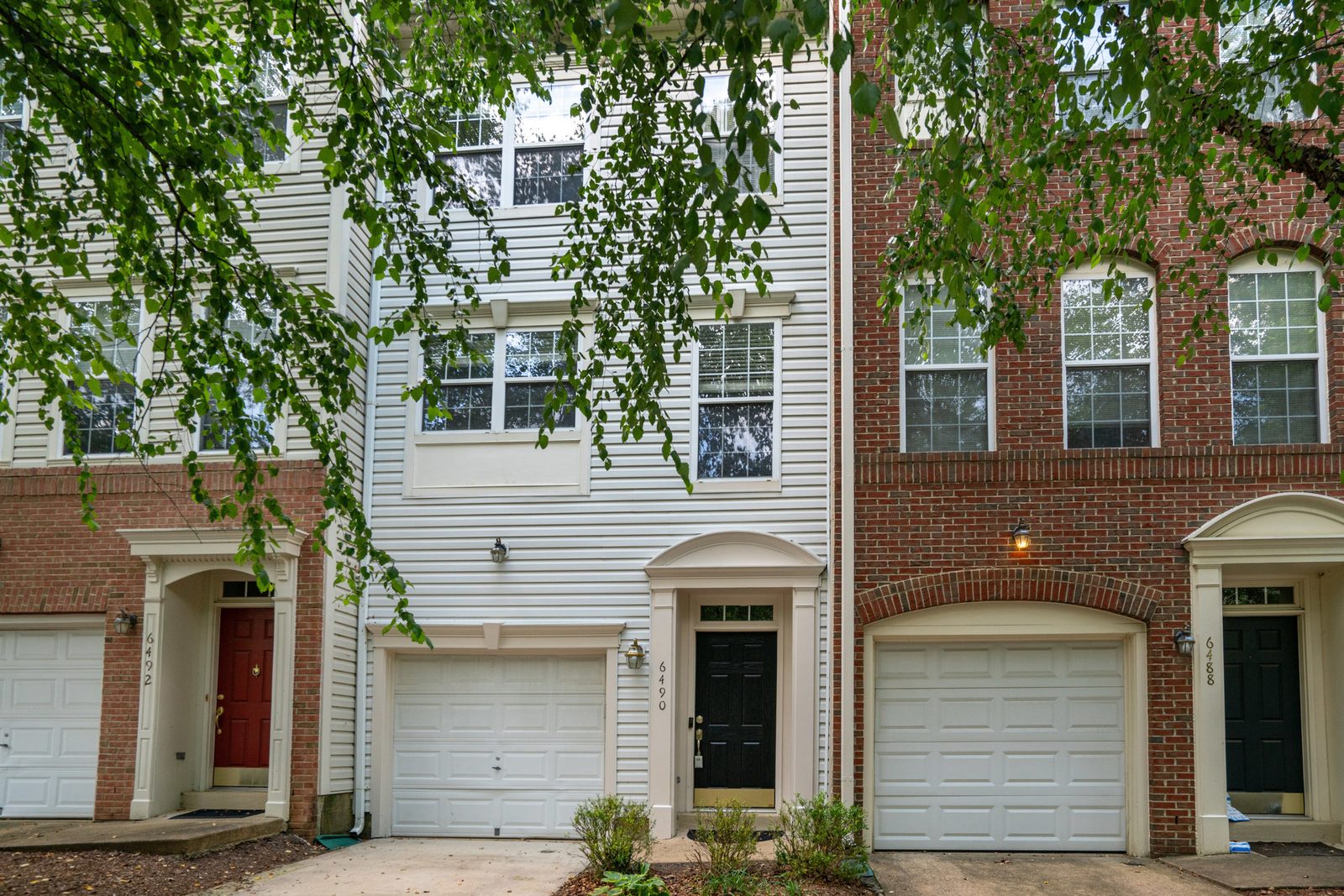 Front exterior of siding townhouse with white single garage door