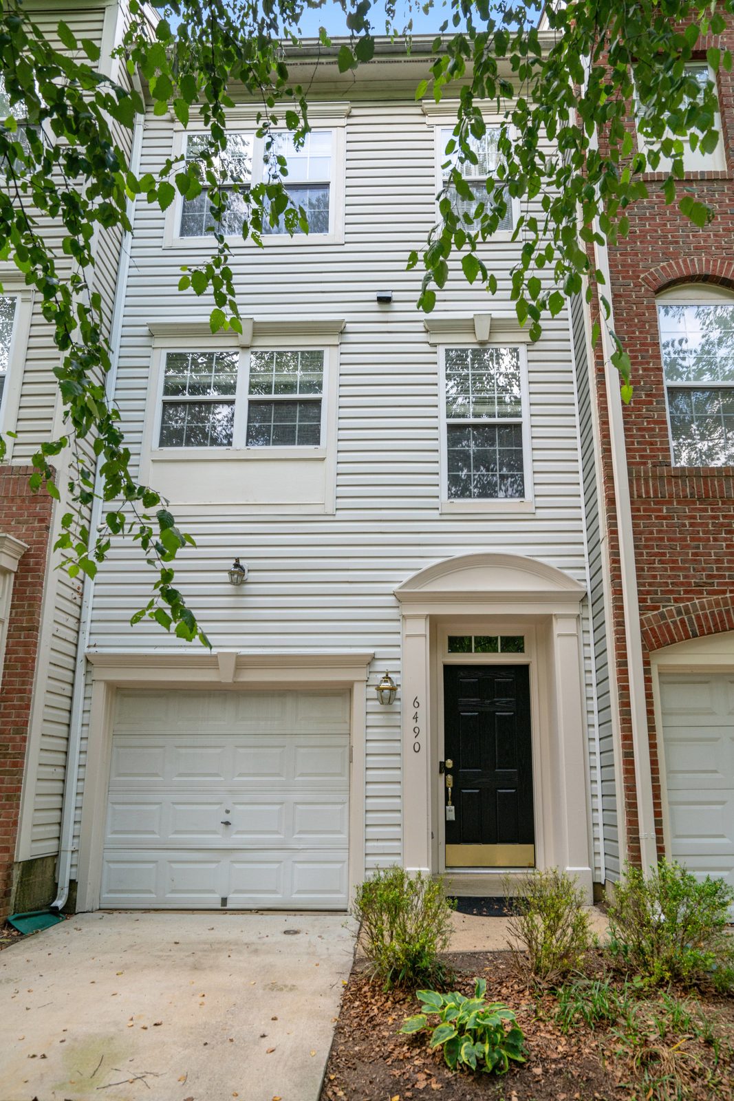 Front entry with black door, arched portico and single garage