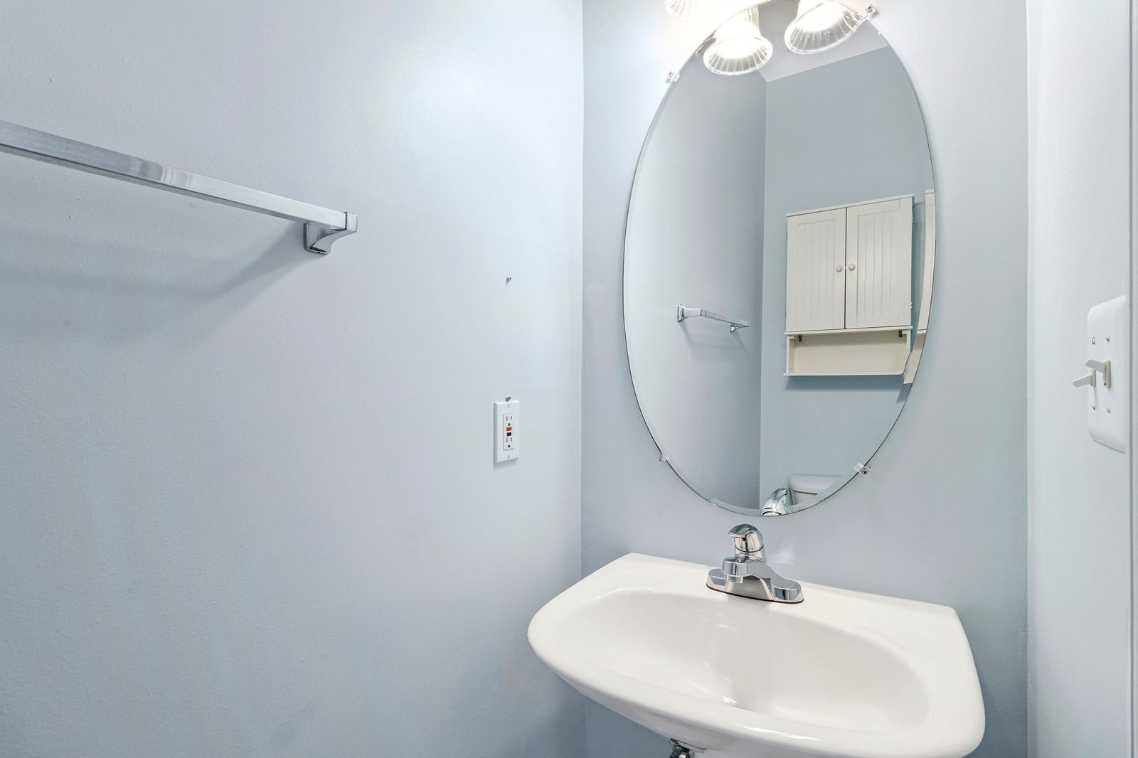 Powder room with pedestal sink, oval mirror and chrome faucet