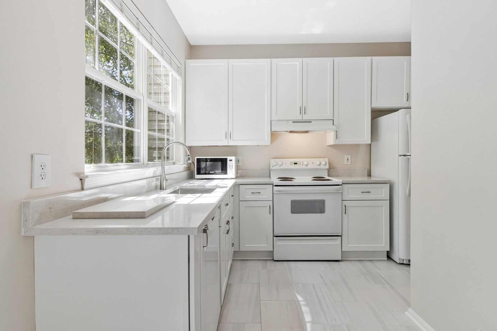 Kitchen with white cabinets, stone-look counters and electric range