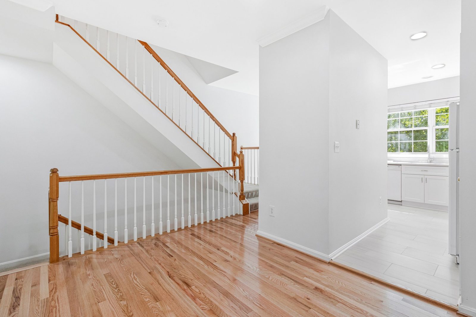 Hardwood landing with oak stair railing and view into kitchen