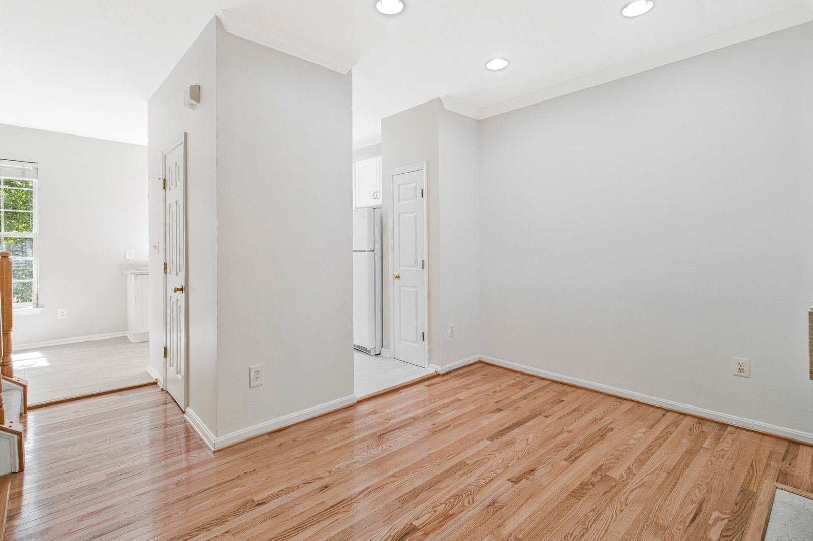 Empty hardwood room with panel doors leading toward the kitchen