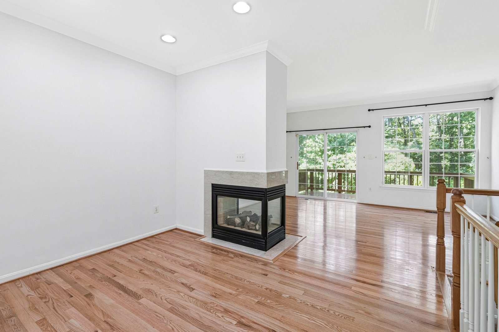 Three-sided fireplace, hardwood floors and sliding door to wooded deck