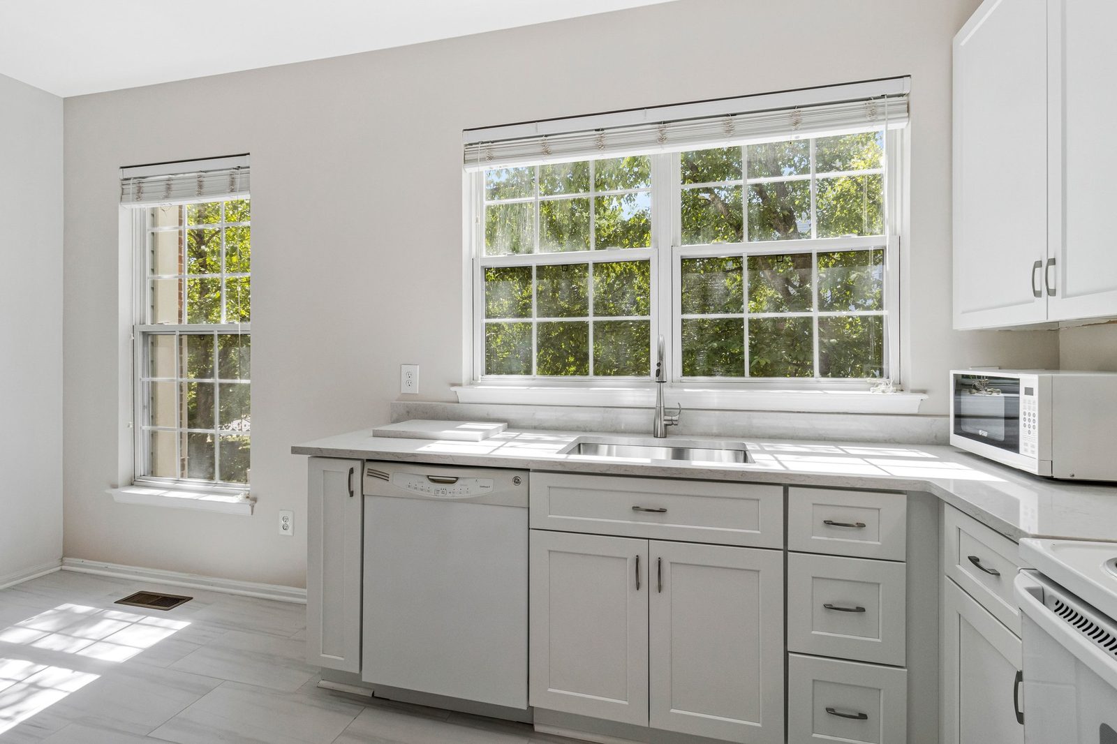 Kitchen with stainless sink under double window and white cabinets