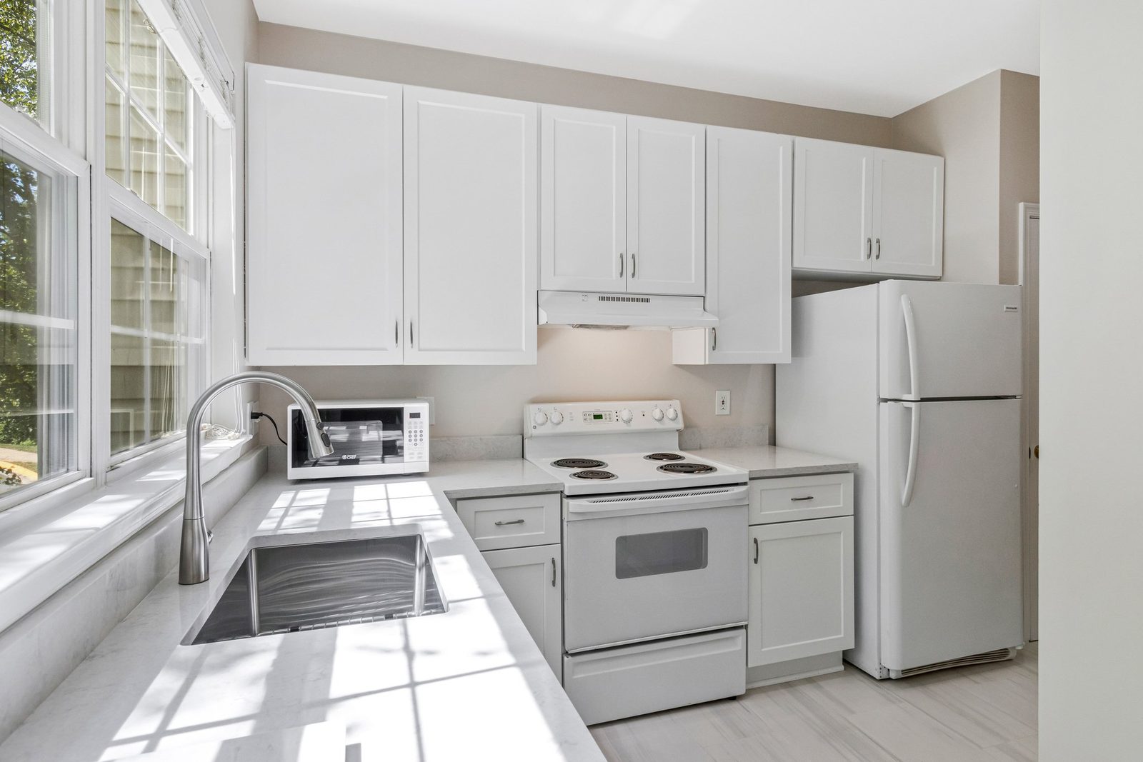 Galley kitchen with white cabinets, electric range and top-freezer refrigerator
