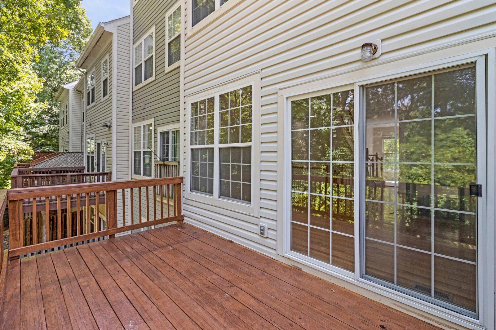 Stained wood deck with railing and sliding glass door